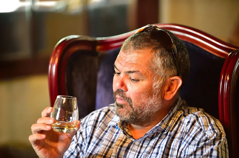 Glass of white wine held up during a vineyard wine tasting